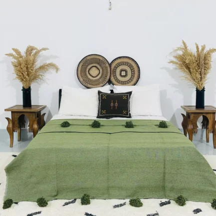 Handmade Moroccan pompom blanket in olive green, styled on a modern bed