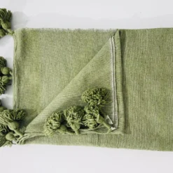 Olive green cotton throw blanket draped over a neutral sofa