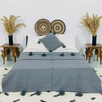 Handmade Moroccan pompom blanket in solid grey, styled on a bed