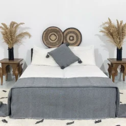 Charcoal grey pompom blanket styled in a minimal boho bedroom