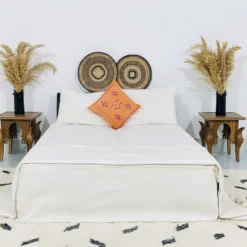 White pompom throw styled on a minimalist bed with neutral decor