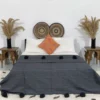 Handmade Moroccan pompom blanket in dark grey on a modern bed