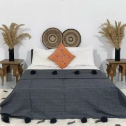 Handmade Moroccan pompom blanket in dark grey on a modern bed