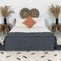 Dark grey Moroccan pompom throw used as a bedspread in modern decor