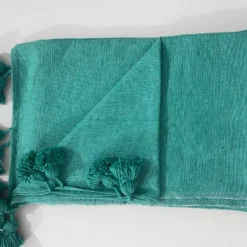 Teal green cotton throw blanket draped on a cozy modern sofa