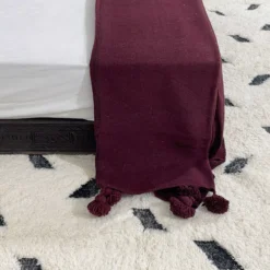 Burgundy cotton throw blanket illuminated by soft natural light