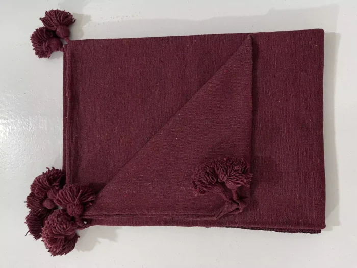 Moroccan cotton throw in burgundy displayed on a cozy modern sofa