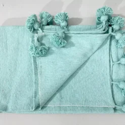 Turquoise cotton blanket catching sunlight in a bright room