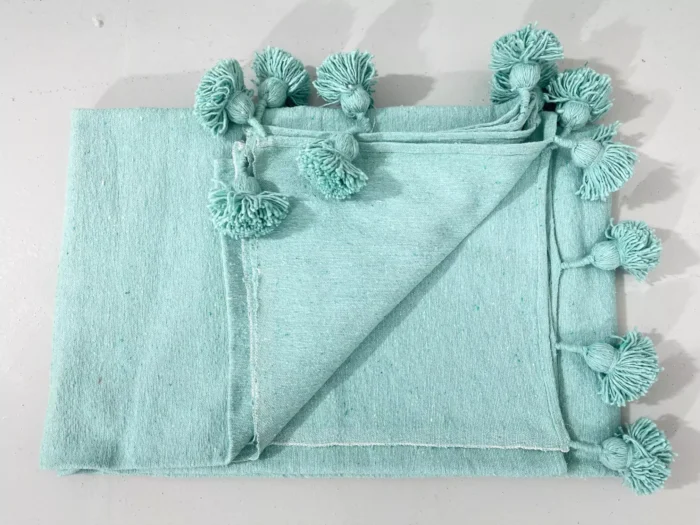 Turquoise cotton blanket catching sunlight in a bright room