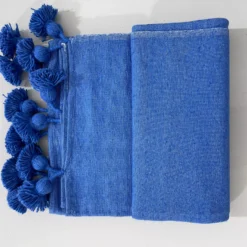 Royal blue cotton throw blanket on a neutral-toned living room sofa