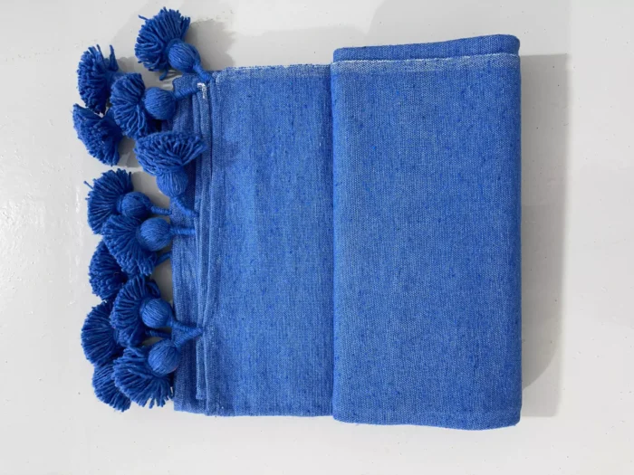 Royal blue cotton throw blanket on a neutral-toned living room sofa