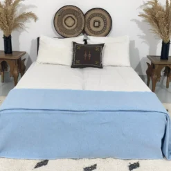 Baby blue pompom blanket styled in a minimalist bedroom