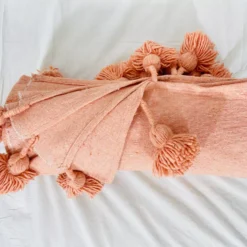 Handwoven salmon blanket catching natural sunlight in a home setting