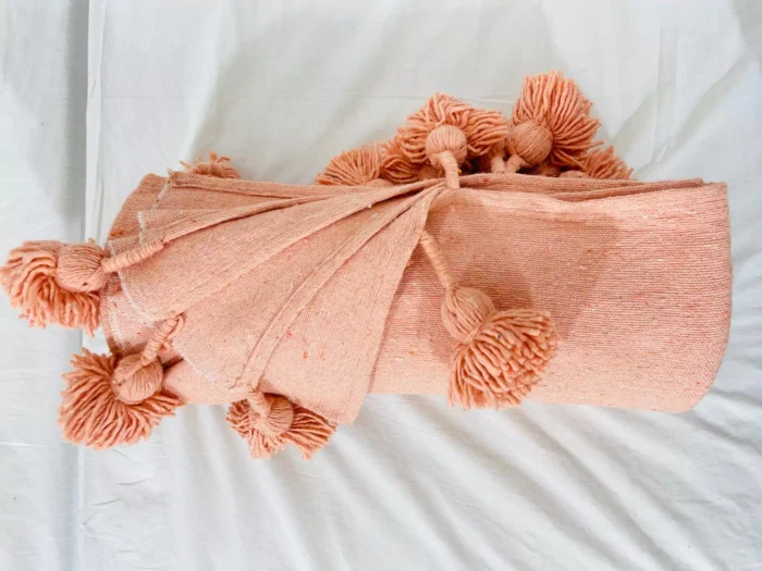 Handwoven salmon blanket catching natural sunlight in a home setting