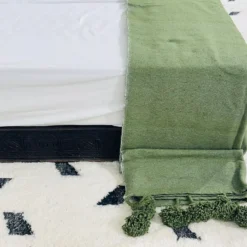 Folded olive green cotton blanket with soft woven texture
