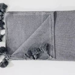 Moroccan throw in charcoal grey draped over a wooden reading chair