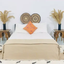 Moroccan pompom throw in beige used as a bedspread in neutral decor
