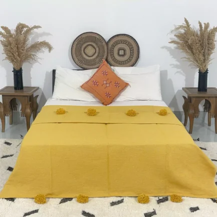 Handmade Moroccan pompom blanket in mustard yellow on bed