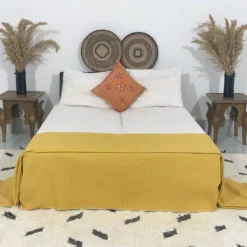 Mustard Moroccan pompom throw on bed with boho-inspired decor