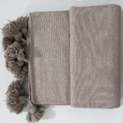 Soft taupe cotton throw blanket styled on a neutral sofa