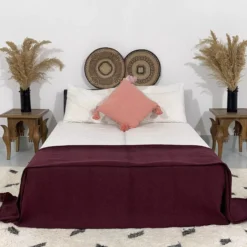 Moroccan burgundy pompom blanket styled in a bohemian bedroom setting