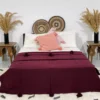 Handmade Moroccan pompom blanket in burgundy on a bed