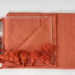Terracotta cotton throw illuminated in soft natural light