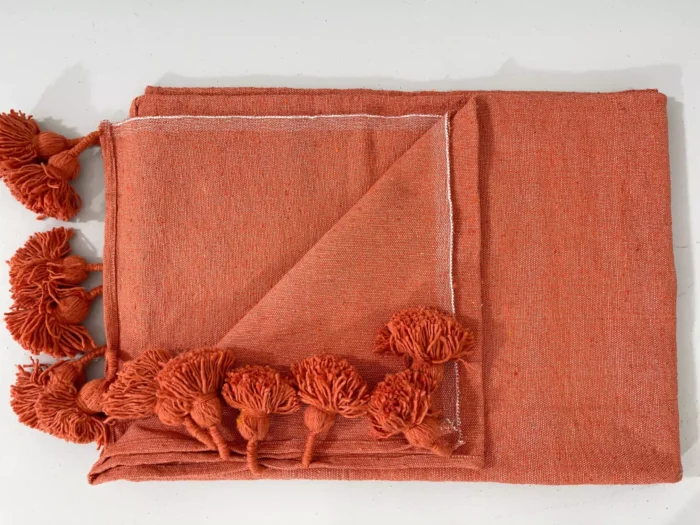 Terracotta cotton throw illuminated in soft natural light