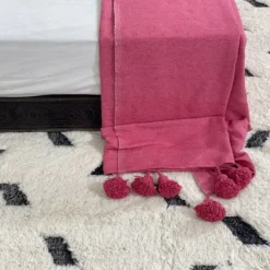 Soft rose pink cotton throw styled on a cozy sofa