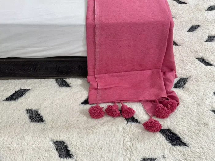 Soft rose pink cotton throw styled on a cozy sofa