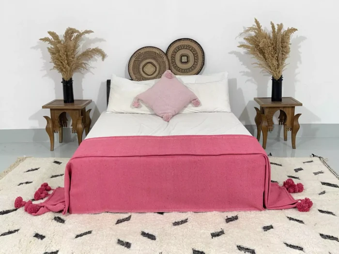 Rose pink pompom blanket styled in a romantic boho bedroom
