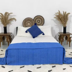 Royal blue pompom blanket styled in a bohemian bedroom