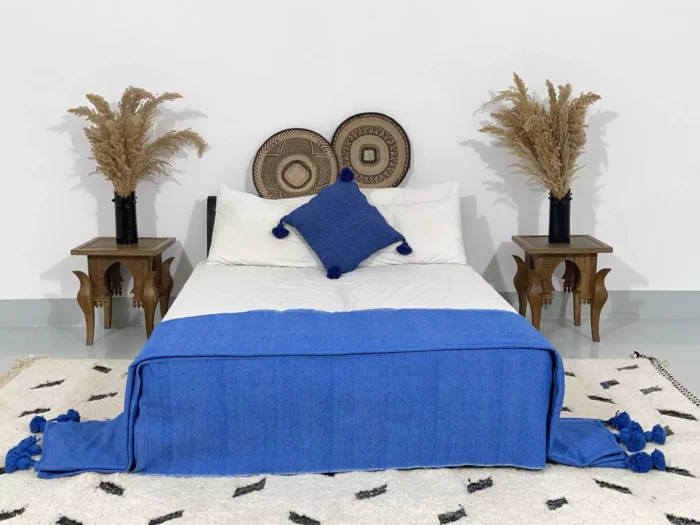Royal blue pompom blanket styled in a bohemian bedroom