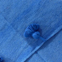 Close-up of royal blue cotton fabric texture and pompom detail
