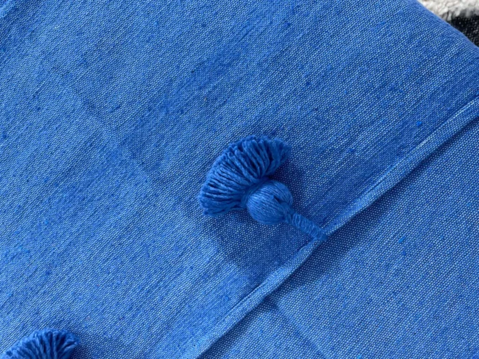 Close-up of royal blue cotton fabric texture and pompom detail