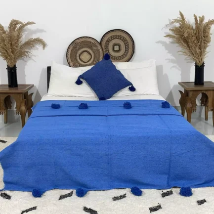 Handmade royal blue Moroccan pompom blanket on a styled bed