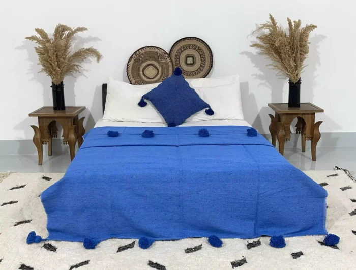 Handmade royal blue Moroccan pompom blanket on a styled bed