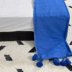 Label tag showing 100% cotton material on royal blue pompom blanket