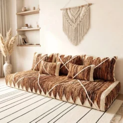 Brown and ivory Moroccan floor sofa styled with wooden shelving and pampas grass in a bright living room