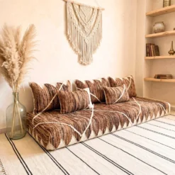 Brown and ivory Moroccan floor sofa in a boho living room with pampas grass and macrame wall hanging