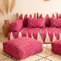 Close-up of pink Moroccan floor sofa pillows and matching floor pouf