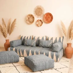 Gray and ivory Moroccan floor sofa with matching poufs and woven wall baskets