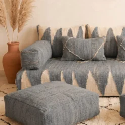 Close-up of gray Moroccan floor sofa armrest with terracotta vase and pampas grass