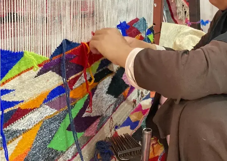 Moroccan artisan weaving a handmade rug on a traditional loom