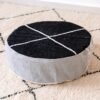 Round cotton pouf with a black top, light grey sides and ivory cross lines