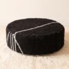 Black round cotton pouf with grouped ivory stripes across the top and side