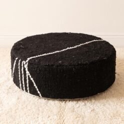 Black round cotton pouf with grouped ivory stripes across the top and side