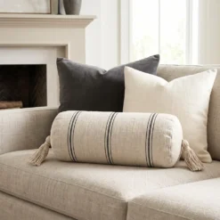 Cream and black striped bolster pillow on a neutral sofa