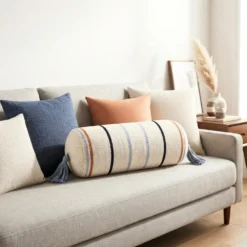 Cream multi stripe bolster pillow styled on a neutral sofa