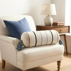 Extra long cream multi stripe bolster pillow across a neutral bed